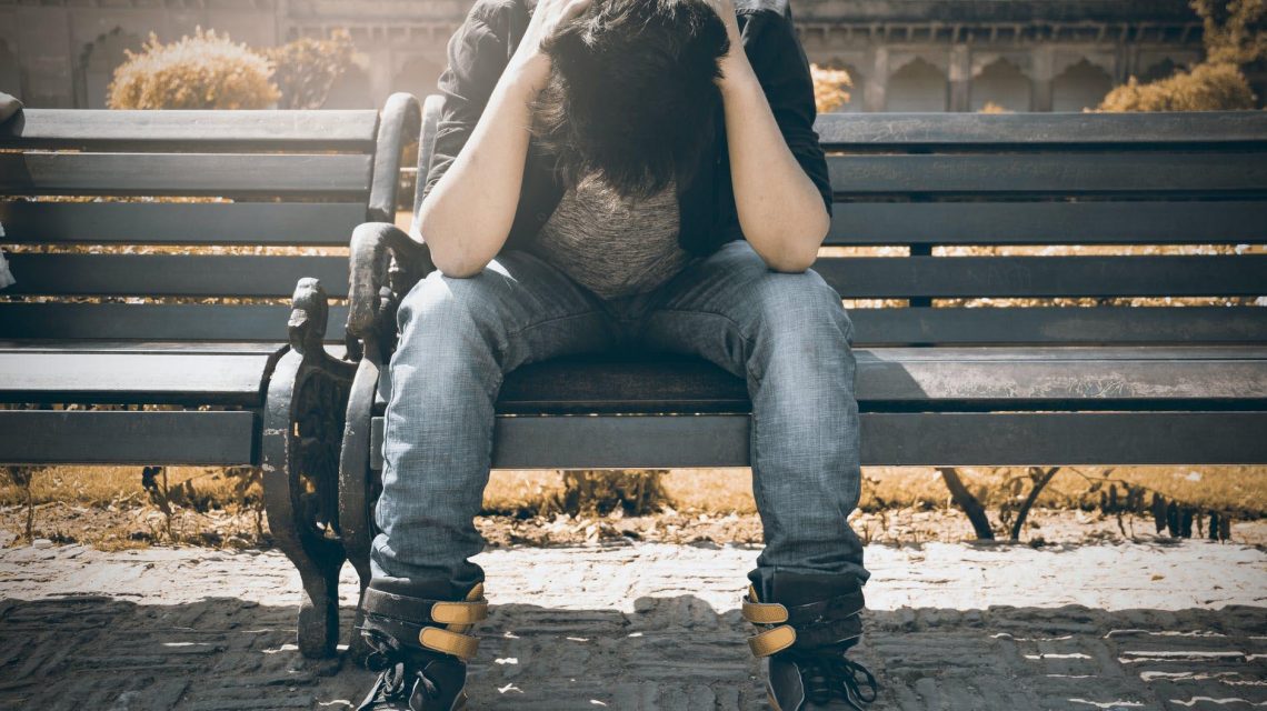 distressed teen male on park bench